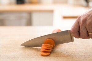Chef's knife slicing a carrot
