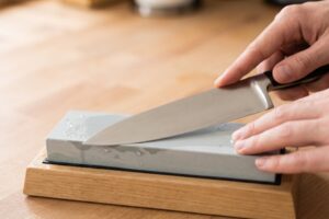 Hands sharpening a kitchen knife on a sharpening stone