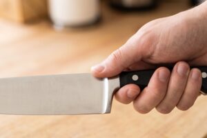 Hand holding a chef's knife with the grip pinched